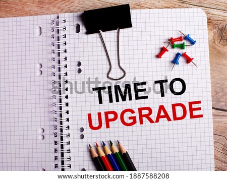 TIME TO UPGRADE is written in a notebook near multi-colored pencils and buttons on a wooden background.