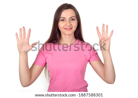 Young woman in pink sweater shows 9 fingers as number nine, isolated on white background.