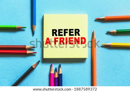 Business concept. List with text Business concept. List with text REFER A FRIEND sheet of YELLOW paper for notes, pencils in the blu background