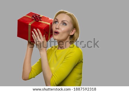 Young excited woman shaking gift box. Young shocked caucasian woman rejoicing her Birthday gift box.