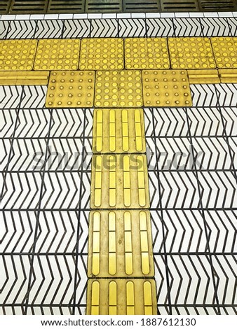 White and yellow patterns on tile platform floor train station Osaka Japan