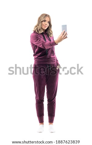 Happy young woman in casual leisure clothes taking photos with smart phone camera. Full body length isolated on white background.