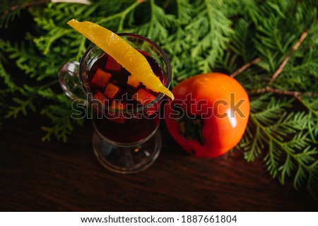 Mulled wine with persimmon and mango on the table in restaurant. Winter and autumn hot alcoholic drink.
