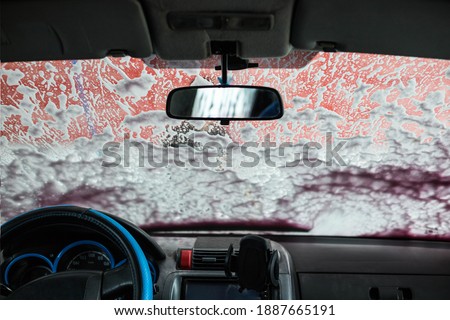 Foam on the windshield. Washing the dirt from the machine with foam. Self-service car wash. Royalty-Free Stock Photo #1887665191