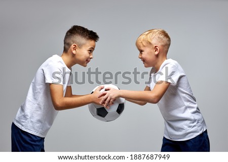 two caucasian soccer players stand opposite each other sharing one ball, looking at each other, going to play, hold match