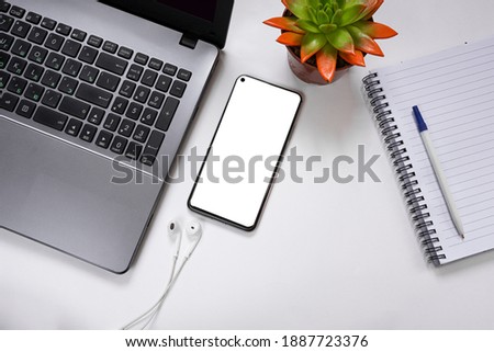 Mockup of a smartphone with a white screen, notebook, notebook, notepad, pen, headphones on a white background. Student desktop concept. copy space. Flat lay. top view
