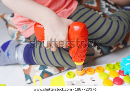 Preschool child development background with baby hand holding toy screwdriver