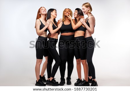 models posing, having fun, laughing isolated on white studio background. interracial multi-ethnic friendship, european african and asian female in sportive wear