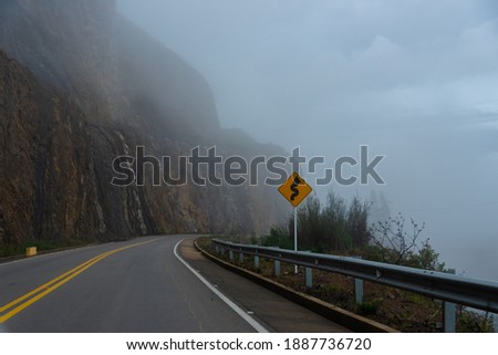 Traffic sign that indicates a curve in the part of a highway between slopes and cliffs. Boyaca. Colombia