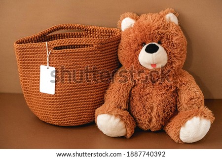Toy teddy bear with a knitted bag on a brown background. Copy, empty space for text.