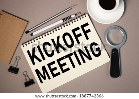 kickoff meeting, text on notepad sheet on brown background near magnifier and coffee cup Royalty-Free Stock Photo #1887742366