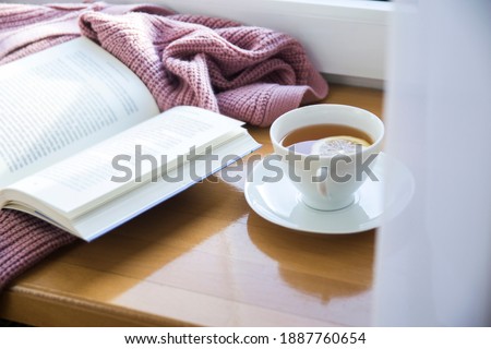 Lifestyle photo with cup of hot tea with lemon, pink sweater and open book. Morning relaxing mood, free time. Royalty-Free Stock Photo #1887760654