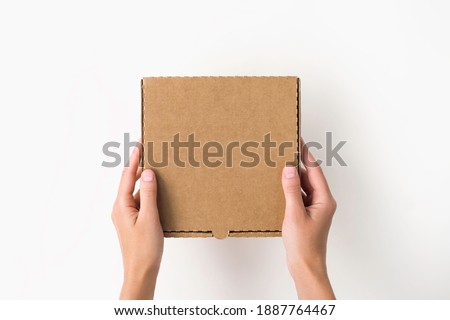 female hands holding a small cardboard box on a white background. packaging and delivery concept, top view Royalty-Free Stock Photo #1887764467