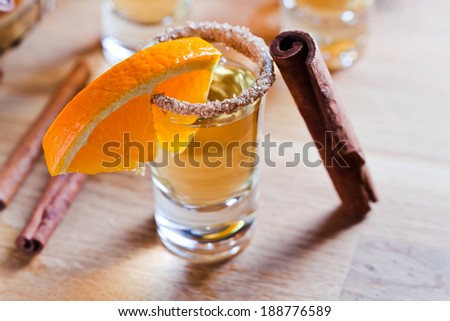 tequila with orange and cinnamon on a wooden table