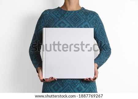 woman holds square family photobook close up with space for text.
sample  white family photo album in womans hands . wedding photoalbum with leather cover isolated on white background.