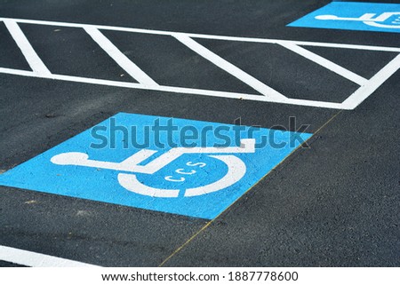Handicap symbol on black pavement in parking lot.