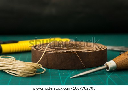 A closeup of a leather strap on top of  a cutting board