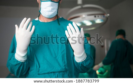 Doctor surgeon and surgical assistant doctor or scrubbing wear surgical gowns and surgical gloves to prepare for surgery before starting the operation, Surgery team ready to work in operating room. Royalty-Free Stock Photo #1887783799