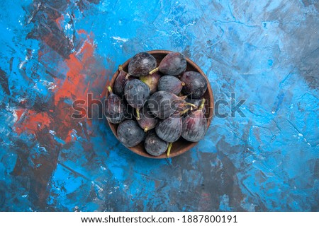 Above view of black mission figs in a small brown pot on blue background