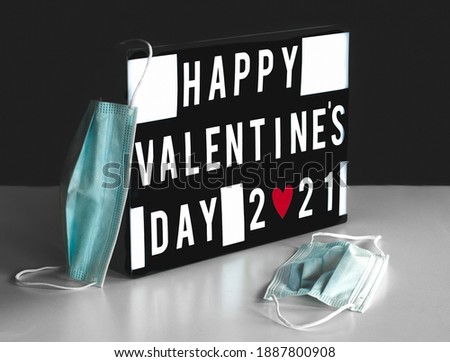 happy valentines day 2021 sign on board and 2 masks, black background, saint valentine.