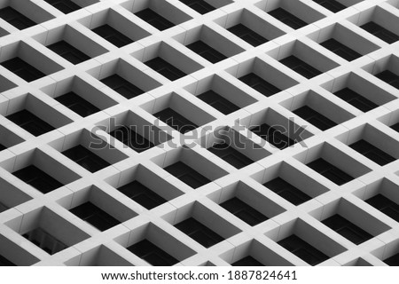 Photo of modern building with modular concrete structure viewed from low angle. Abstract architecture with cellular geometric pattern. Minimal black and white regular grid with rectangular elements.
