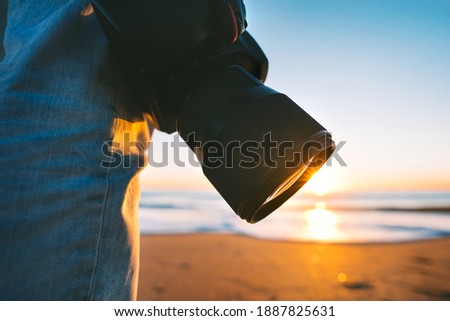 Professional photographer with his camera on the beach at sunset ready to take beach pictures. Beach photography.