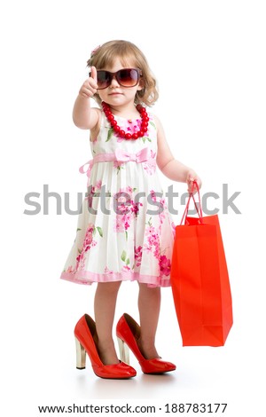 Funny kid girl trying on her mom's red accessories and shoes
