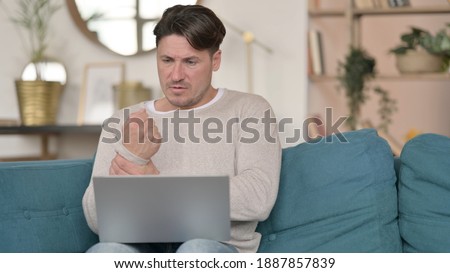 Middle Aged Man with Laptop having Wrist Pain at Home