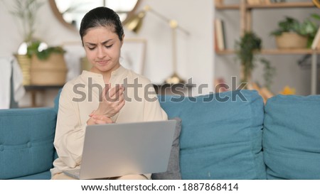 Young Indian Woman with Laptop having Wrist Pain on Sofa