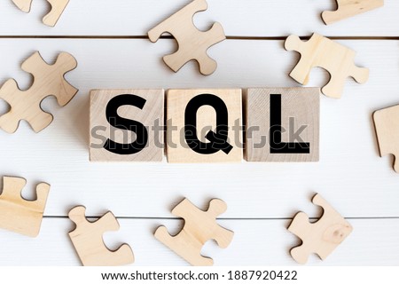 SQL word on wooden cubes on a white background, near wooden puzzles