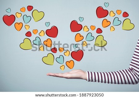 A picture of a woman's hand Wear a long-sleeved shirt with a black and white pattern, with hearts of various colors and sizes floating out of the palm, suitable for use. Media of Valentine's Day.