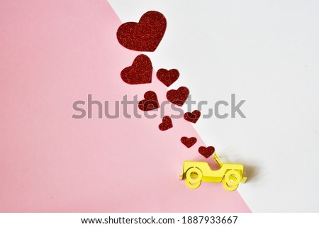 Yellow toy car with red hearts for Valentine's day on pink-white background. Valentine's Day card. Holiday concept. Mather's day. Valentine's Day background.