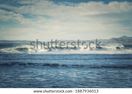 Scenic seascape. Stormy waves, moutains and cloudy sky on background, California