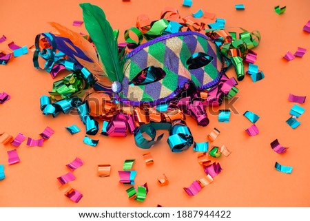 Classic colorful carnival mask with feathers and confetti on colored background. Concept of costume festivals, parades and carnivals.