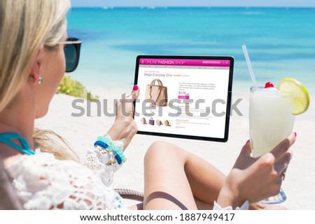 Woman looking at new bag in online store while relaxing on the beach