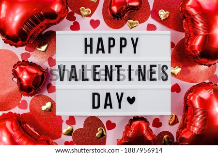 Stylish text frame lightbox with the inscription happy Valentine's day. Pink, red and beige hearts all around. Foil balloons top view of Valentine's Day. Copyspace. Royalty-Free Stock Photo #1887956914