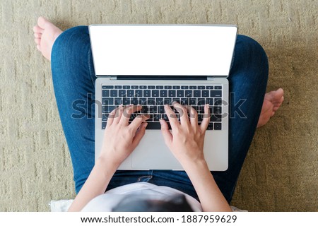 Young woman working on a laptop sitting on sofa at home.