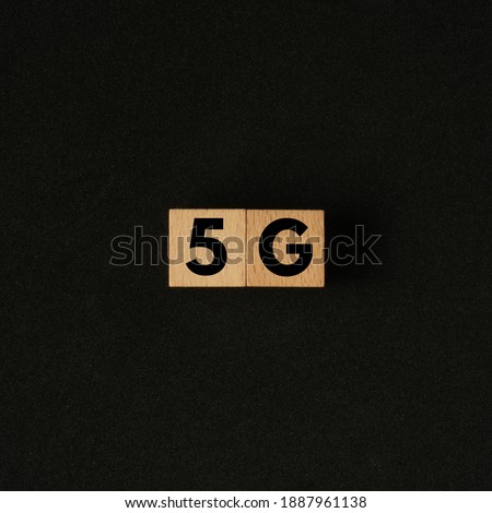 5G word on wooden cube. Flat lay view concept on black background. Square size of photo.