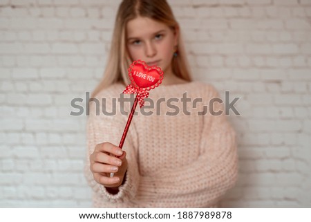 Girl holding red fabric heart with I love you sign on stick, Valentine's day background