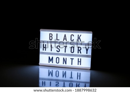 Lightbox with text BLACK HISTORY MONTH on dark black background with mirror reflection. Message historical event. Light
