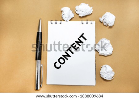 Crumpled sheets of paper are scattered around a notepad on which the word content is written. Concept photo