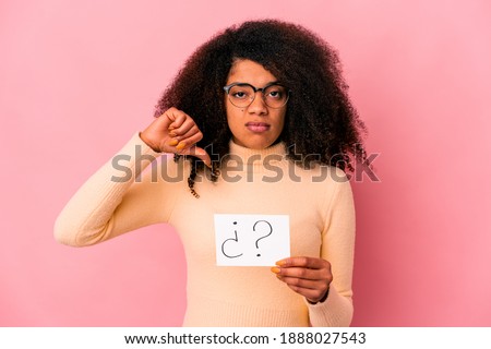 Young african american curly woman holding an interrogation on a placard showing a dislike gesture, thumbs down. Disagreement concept.