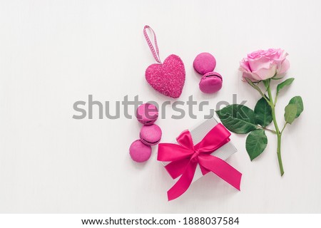 Valentine's Day. Beautiful composition - roses, gift box, purple macaroons and heart. White painted wood background. Greeting card. Top view, flat lay