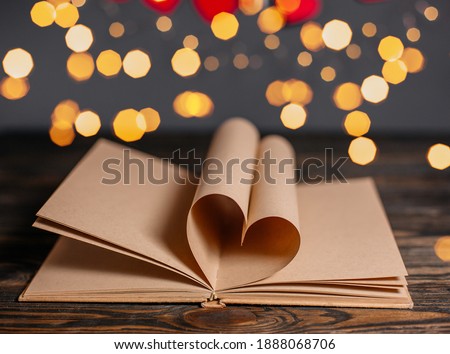 Heart made from book sheets in lights, love and valentine concept on a wooden table