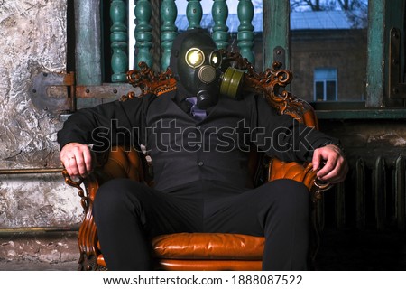 cosplay of a guy in a gas mask sitting on a leather chair with glowing eyes