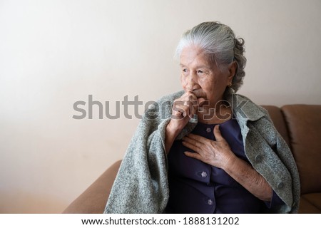 Asian senior ill female have a cough and sore throat. Causes of cough include common cold, flu, respiratory tract infection, pneumonia, bronchitis, allergy or asthma. Elderly health care concept. Royalty-Free Stock Photo #1888131202