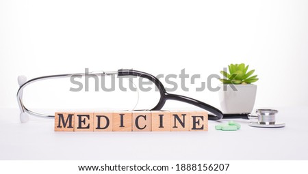 Medicine concept. Panoramic banner close up view photo of nurse instrument plant in a pot pile of pills and wooden blocks showing inscription medicine isolated white background
