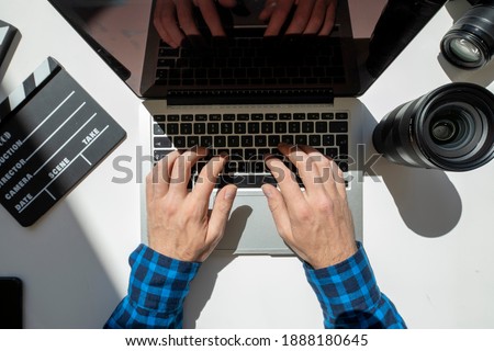 Top view shot closeup of film maker sitting on desk writing on a laptop with floating sun