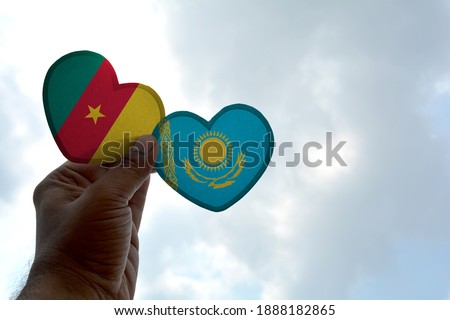 Hand holds a heart Shape Cameroon and Kazakhstan flag, love between two countries