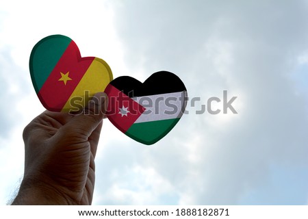 Hand holds a heart Shape Cameroon and Jordan flag, love between two countries